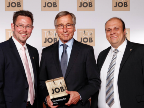 2014-480x360 Drei Männer in Anzügen posieren mit einer Top Job-Auszeichnung vor einem Markenhintergrund.