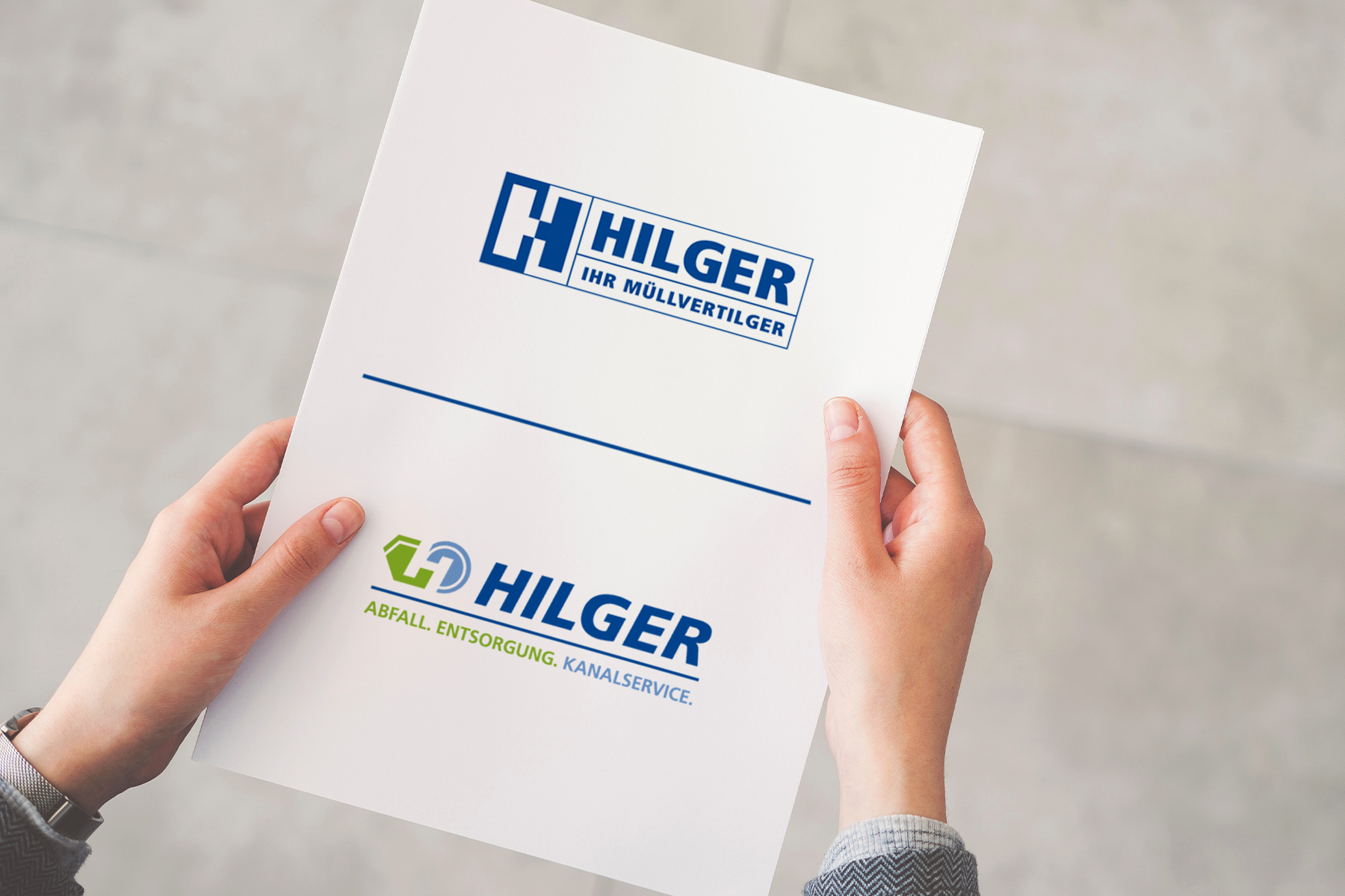 Person, die eine Mappe mit zwei Hilger-Firmenlogos und ihren jeweiligen Slogans in der Hand hält.