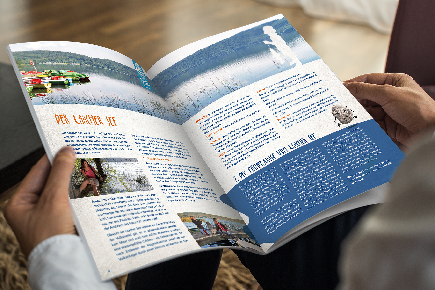 Person hält und liest eine deutschsprachige Zeitschrift mit Geschichten und Fotos über einen See.