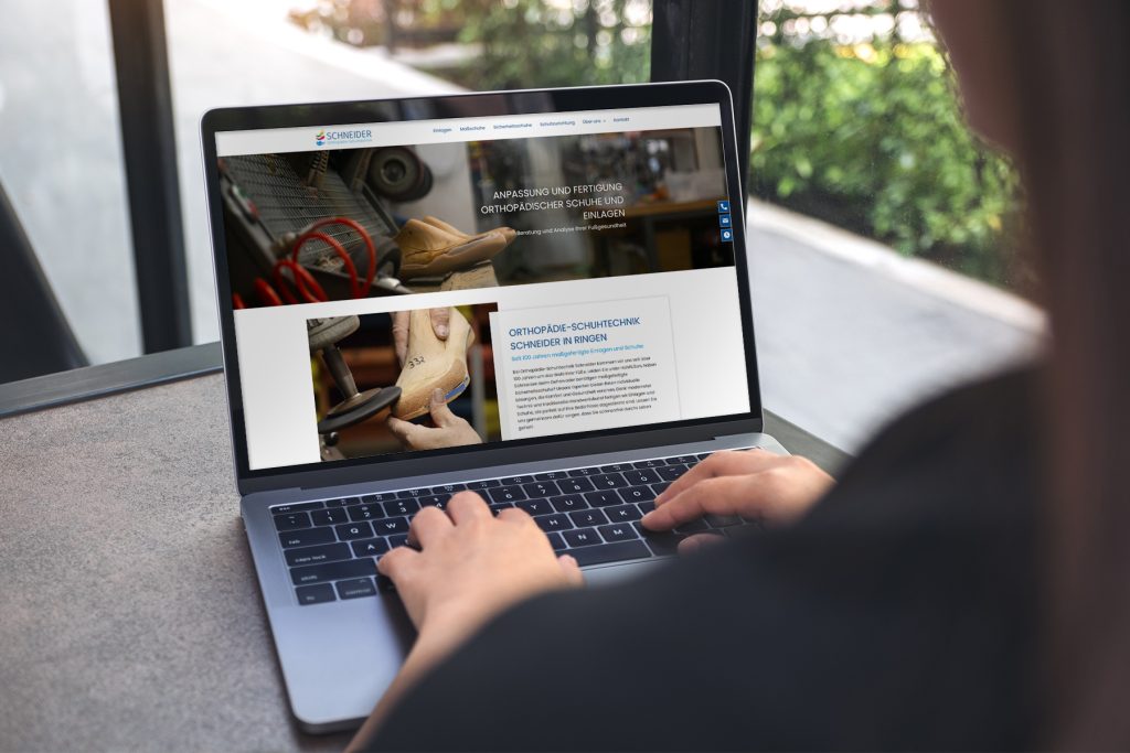Person mit einem Laptop, der eine Website über orthopädische Schuhtechnik anzeigt.