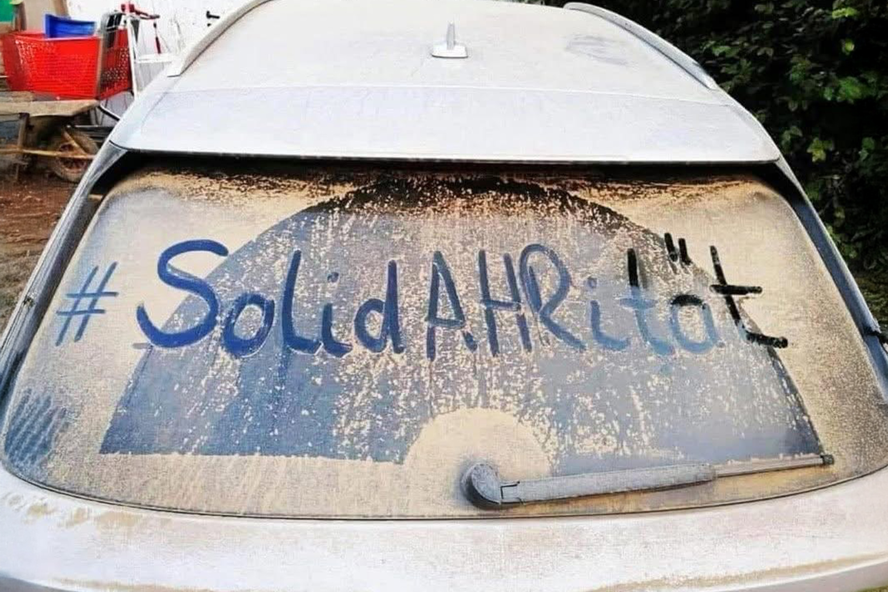 Das Wort #Solidarität steht auf einer staubigen Autoheckscheibe.