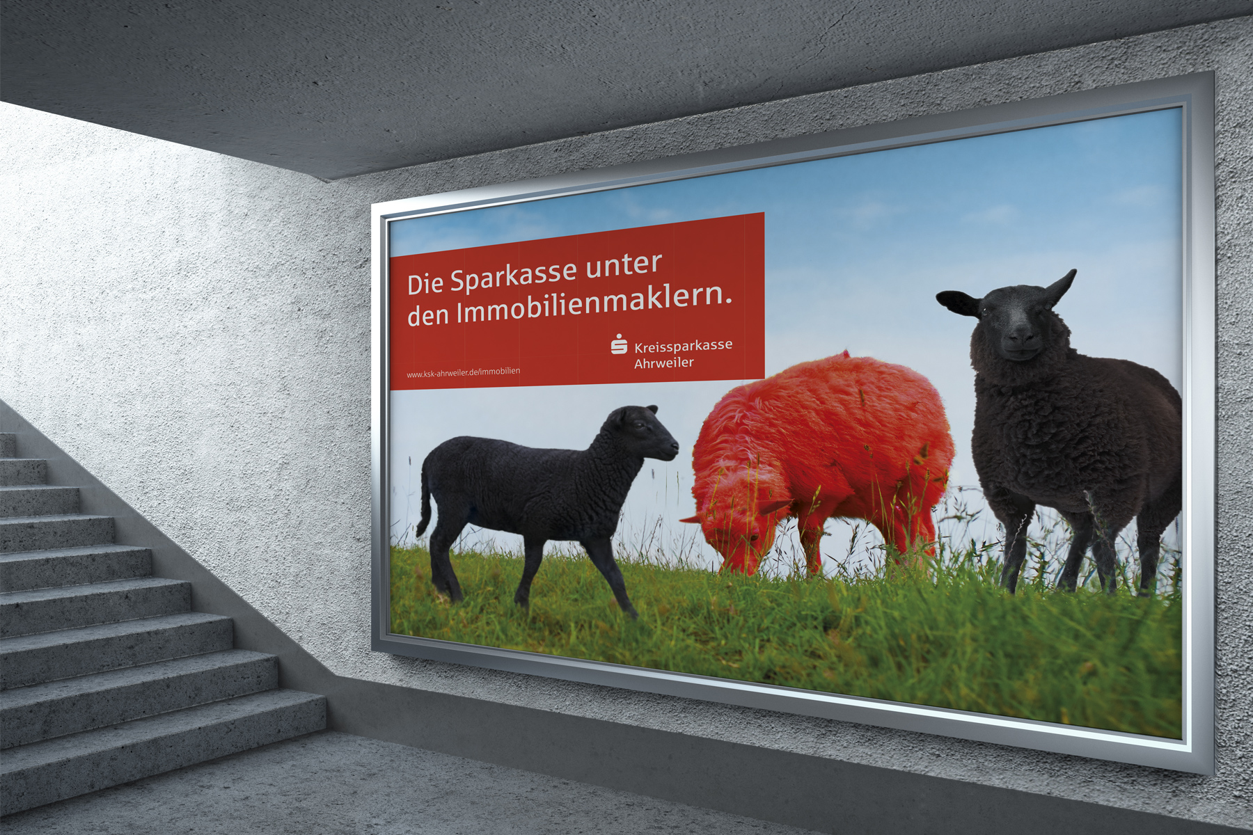 Plakatwerbung mit drei Schafen, von denen eines rot angemalt ist, mit deutschem Text über Immobiliendienstleistungen.