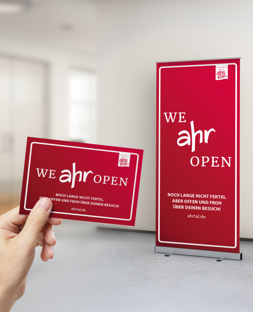 Eine Hand hält eine rote, aufgeschlagene We ahrkarte vor einem passenden vertikalen Banner.