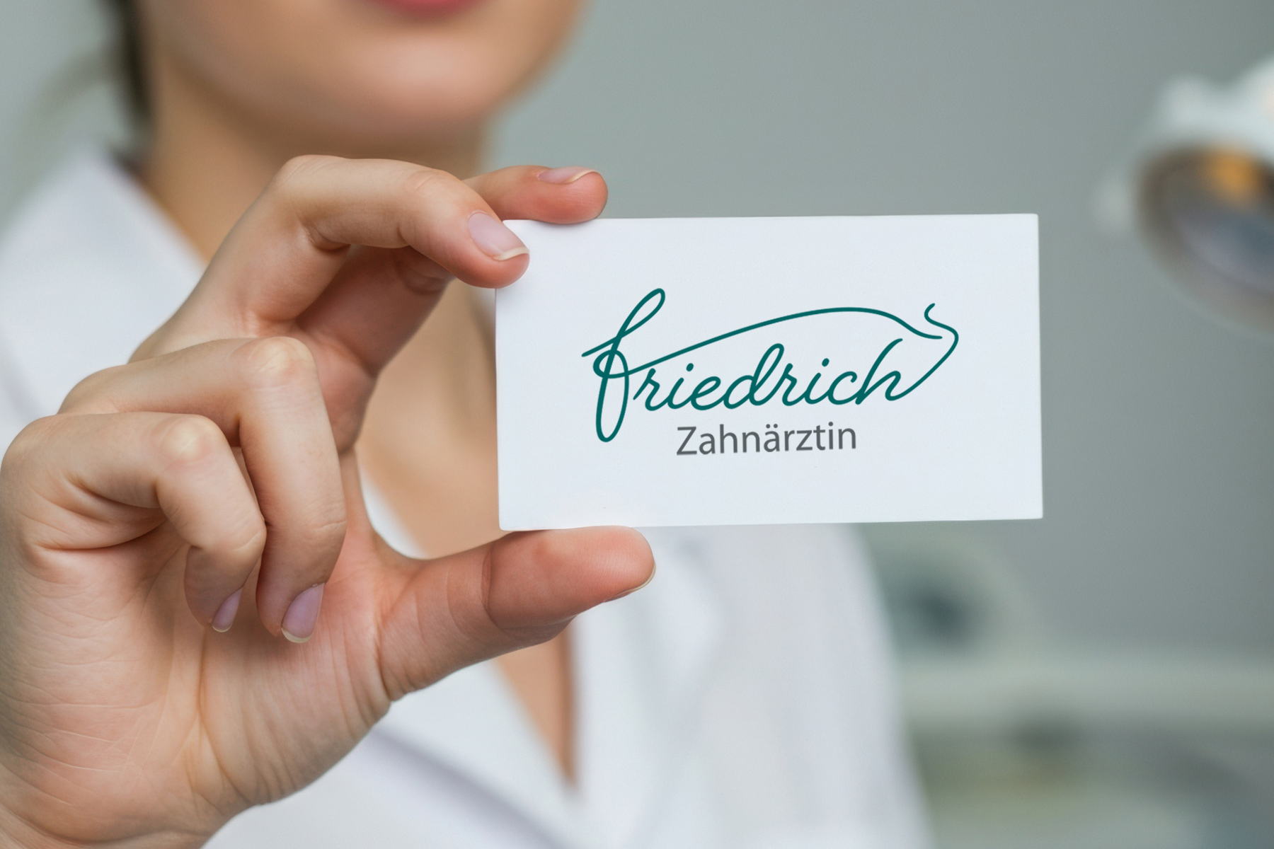 Eine Person, die eine Visitenkarte in der Hand hält, auf der in Schreibschrift und Druckbuchstaben „Friedrich Zahnärztin“ steht.