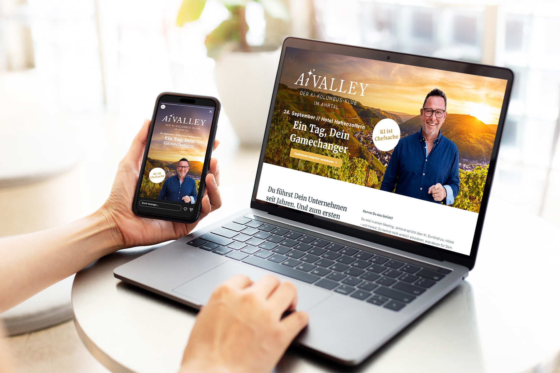 Eine Person, die ein Smartphone in der Hand hält und an einem Tisch sitzt, auf dem ein Laptop steht, auf dem dieselbe Website angezeigt wird.